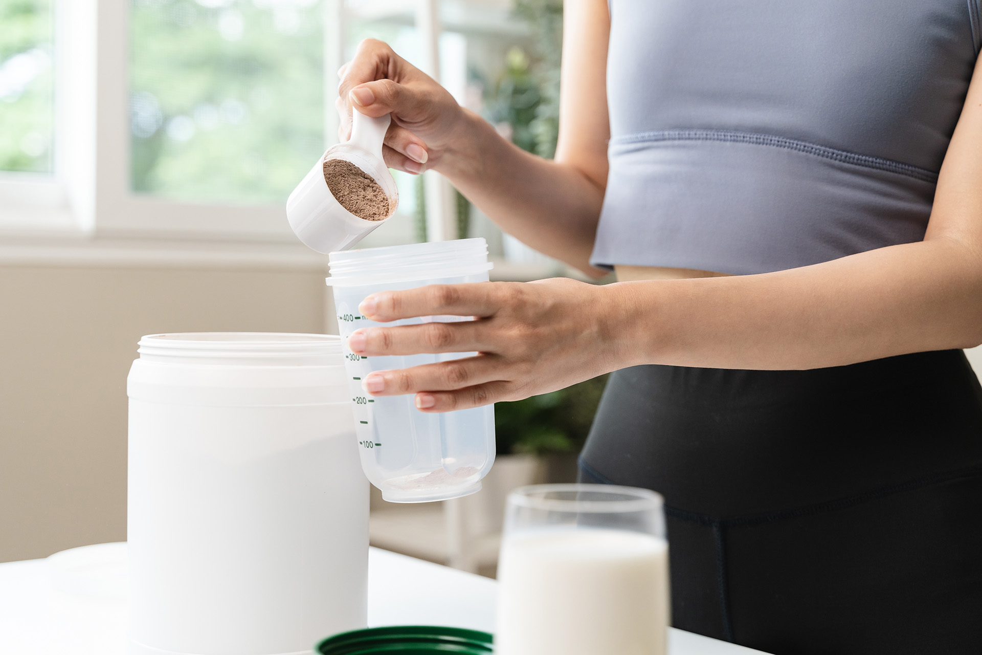 Young woman pouring protein powder into a cup. Nutraceuticals packaging and labels