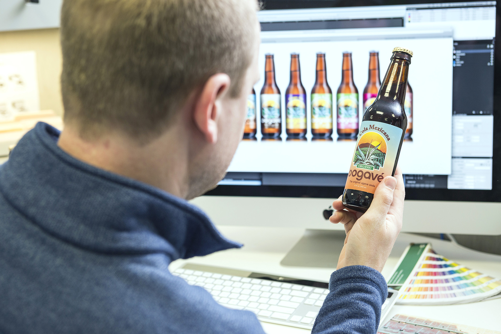 Prepress team member with pressure sensitive label on craft beer bottle