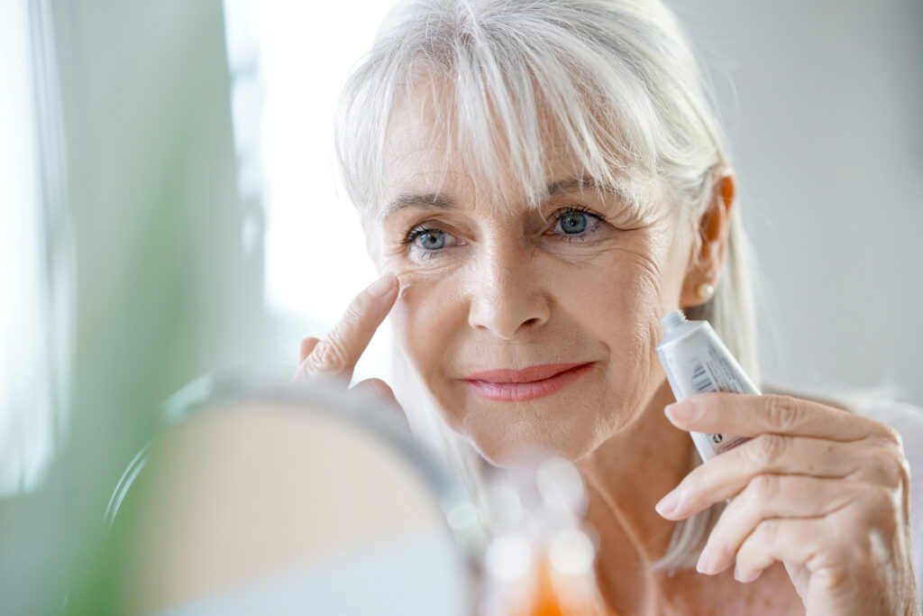 Portrait of senior woman applying cream. custom printed cosmetics labels and packaging