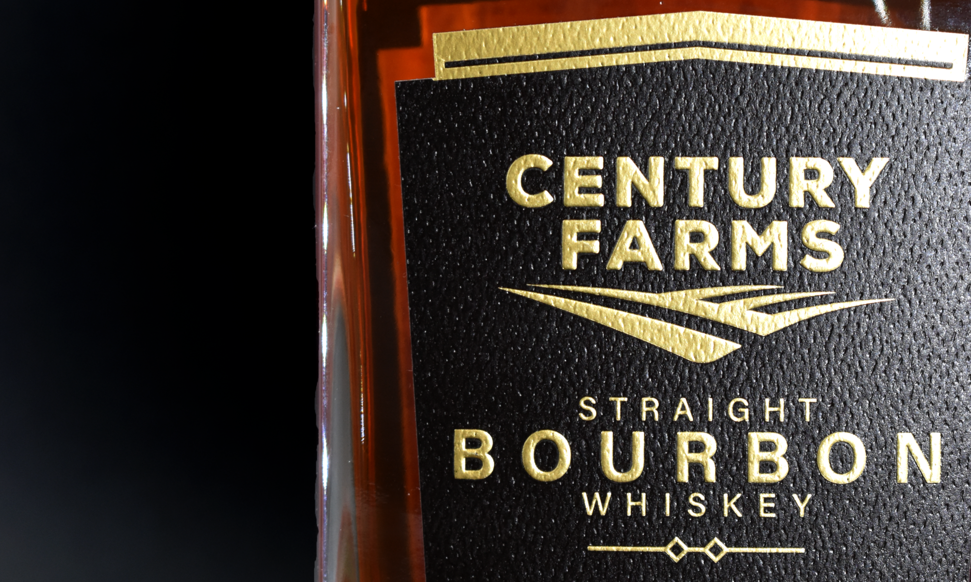 Close-up of a bourbon bottle with a custom embellished label by Brook + Whittle, featuring intricate embossing and gold hot stamp foils, highlighting premium label craftsmanship.